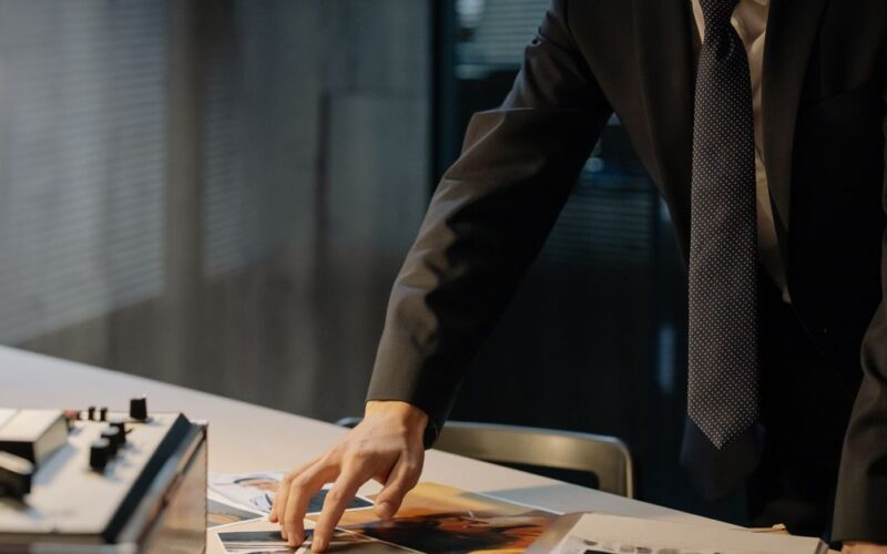 fraudes no INSS — Investigator reviewing evidence photos during a night investigation in an office setting.